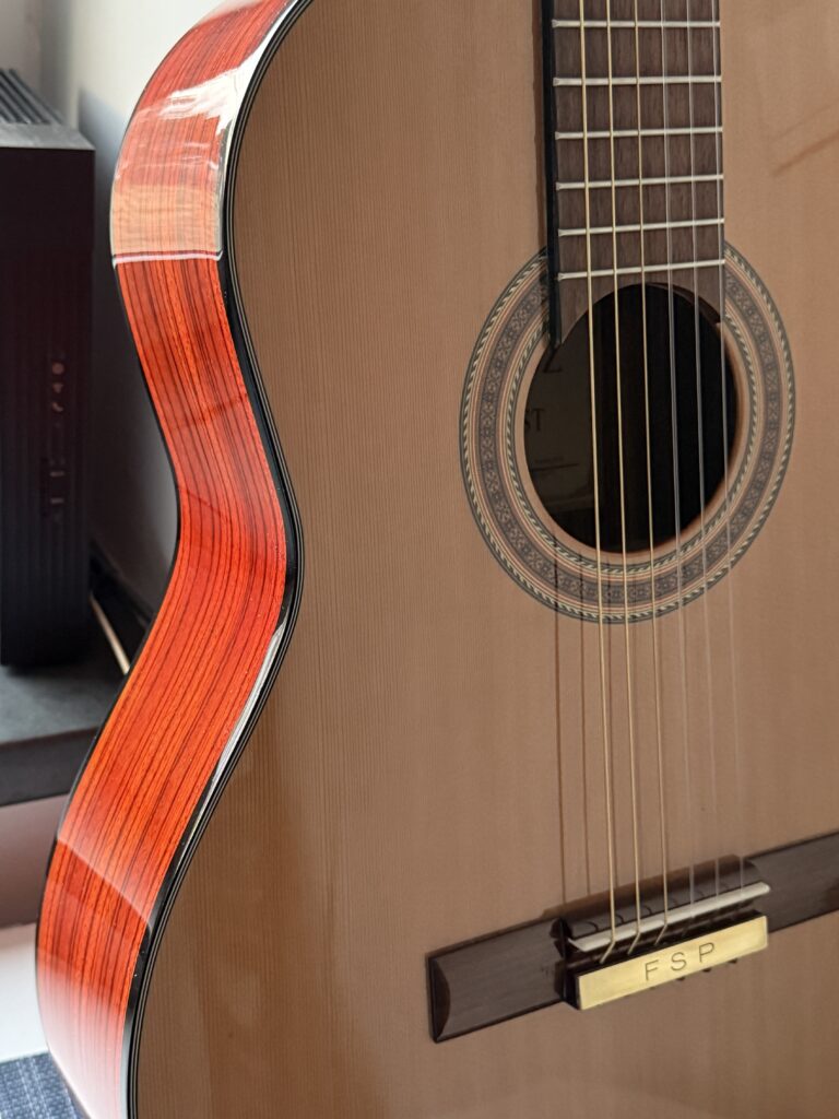 A Casarez SLR 380 classical guitar with a natural wood finish and a decorative soundhole rosette.